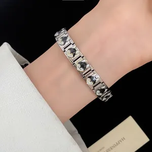 Detailed view of a stainless steel modular bracelet with black and white dog head motifs