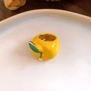 Primer plano detallado que muestra el anillo de manzana en esmalte amarillo con hoja verde y oro