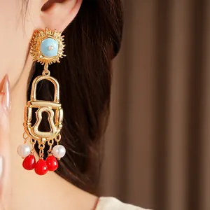 Close-up of gold-plated lock earrings featuring pearl and red tassel accents