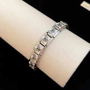 Macro view of stainless steel charm bracelet with cute enamel pug dog pattern details.