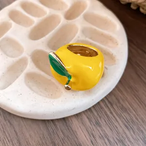 Primer plano detallado de un anillo manzana de esmalte amarillo con hoja y oro