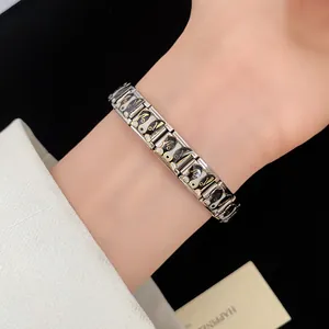 Detail view of a stainless steel bracelet featuring black and white puppy enamel charms.