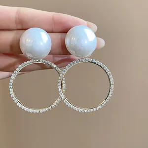 Detalle de pendientes de perlas grandes con aros circulares de cristales