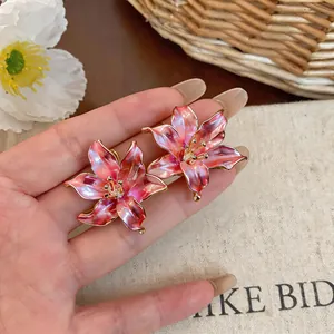 Primo piano di orecchini a lobo a forma di fiore rosa con eleganti bordi dorati