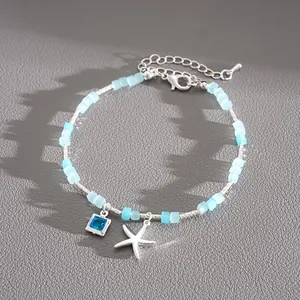 Dettaglio di un braccialetto di perline blu con ciondoli a stella marina e cristallo blu