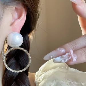 Detalle macro de elegantes pendientes de perla redonda con aro de diamantes y pin de plata