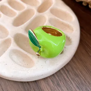 Primer plano detallado de un anillo de manzana verde esmaltado con borde de oro