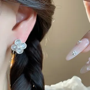 Close-up of sparkling zircon four-leaf clover flower earring on model's ear