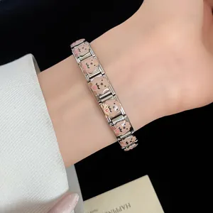 Close-up detail of stainless steel charm bracelet featuring cute enamel puppy designs on wrist
