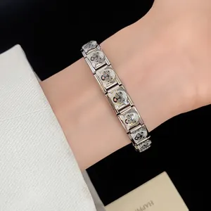 Detailed macro view of a stainless steel enamel pug dog bracelet worn on a wrist