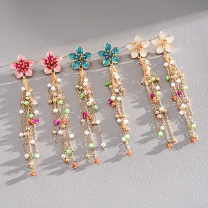 Close-up detail of enamel flower tassel earrings with colorful beads and pearls