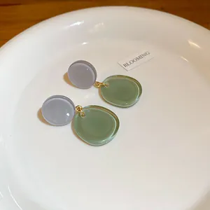 Gros plan sur d'élégantes boucles d'oreilles en résine vert forêt dans un plat blanc chic