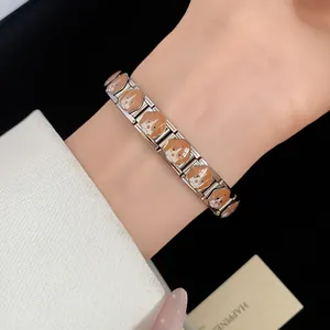 Close-up detail of stainless steel link bracelet with brown enamel dog patterns