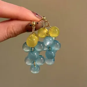 Vue macro détaillée de boucles d'oreilles pendantes en perles de résine bicolores.