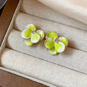 Gros plan détaillé de boucles d'oreilles fleurs en résine verte et blanche en boîte