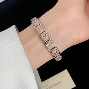 Close-up of a stainless steel bracelet featuring adorable brown enamel dog charms on a wrist