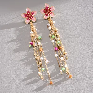 Close-up of pink enamel flower tassel earrings with pearls and colorful beads