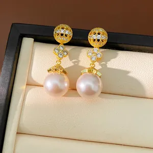 Detailed close-up of gold-plated clover pearl earrings with shimmering zircon accents