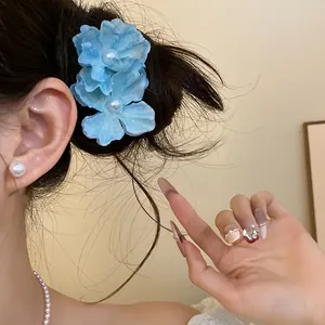Detail view of sweet blue fabric flower hair clips worn on side hair for seaside style