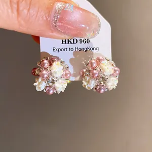 Dettaglio di eleganti orecchini a lobo a fiore con perle rosa e strass brillanti