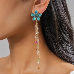 Close-up detail of blue enamel flower earring with elegant long pearl and bead tassels