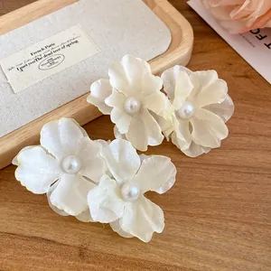 Close-up of white fabric flower hair clips with elegant pearl centers for women.