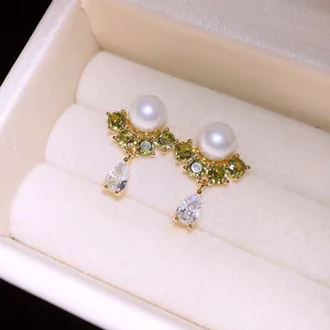 Close-up of 14k gold plated stud earrings with pearls and green zircon accents