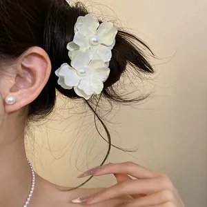 Close-up view of a sweet cream fabric flower hair clip with pearls on a model's hair bun