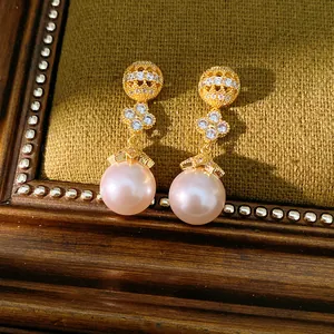 Close-up of elegant 18k gold plated clover earrings with zircons and pink pearl drops