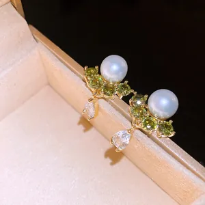 Exquisite close-up of 14k gold plated pearl earrings with green zirconia stones