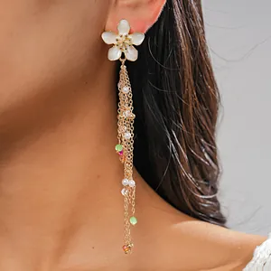 Close-up of elegant flower tassel earrings with pearls and colorful glass beads on a model.