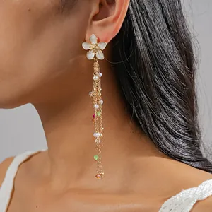 Detail view of white flower tassel earrings with pearls and colorful beads on a model.