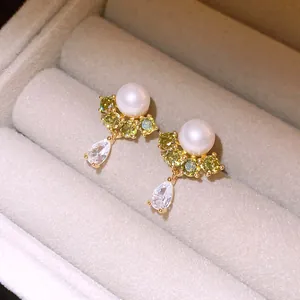 Close-up of 14k gold-plated pearl and zircon earrings in a beige velvet jewelry box
