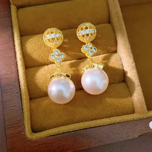 Detail of gold-plated clover earrings with crystals and pink pearl drop
