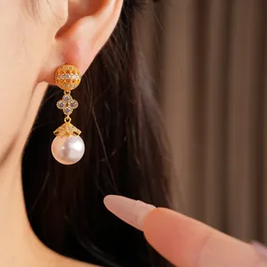 Close-up of 18k gold plated clover zircon drop earrings with large white pearl detail.