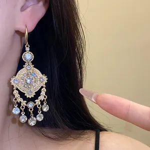 Close-up of vintage palace style gold drop earrings with rhinestones and wheat motifs