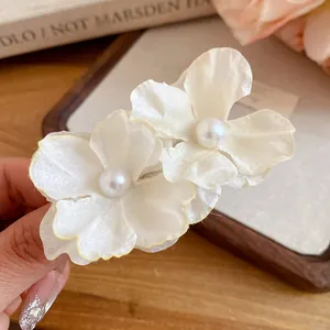 Detailed view of white fabric flower hair clip with elegant pearl center and soft texture