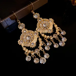 Close-up of vintage palace style gold dangle earrings with wheat leaf and rhinestone details.