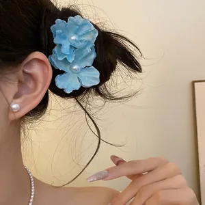 Close-up view of a sweet blue fabric flower hair clip with central pearl accents