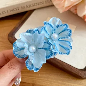 Detailed view of sweet blue fabric flower hair clip featuring an elegant pearl center