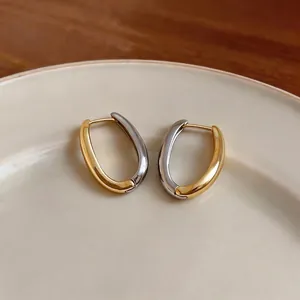 Eleganti orecchini a cerchio bicolore vintage in oro e argento su un piatto di ceramica