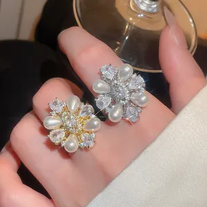 Close-up of gold and silver flower rings featuring pearls and sparkling zircons