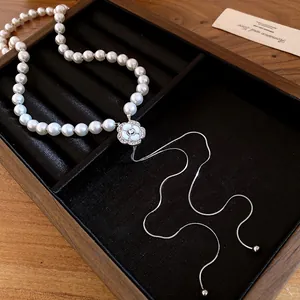 Detail view of pearl necklace with rhinestone flower pendant and elegant tassel chain