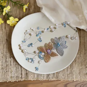 Vista dettagliata della collana multistrato con perle e fiori in filo su piatto bianco
