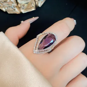 Close-up of a luxurious purple teardrop zircon ring with double halo pavé setting