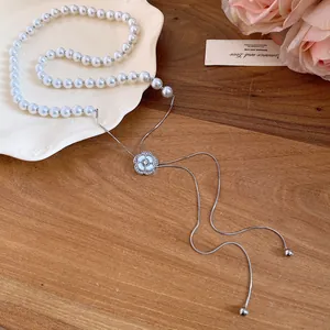 Detailed view of a pearl necklace with a sparkling camellia flower charm and elegant tassels.
