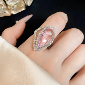 Close-up view of elegant teardrop pink zircon ring with micro-pave crystals on finger.