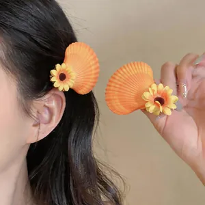 Gros plan détaillé d'une pince à cheveux barrette avec coquillage orange et fleur jaune