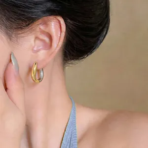Vista dettagliata di orecchini a cerchio minimalisti bicolore oro e argento indossati da una modella