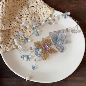 Dettaglio della collana di perle a più strati con eleganti ciondoli a fiore in maglia